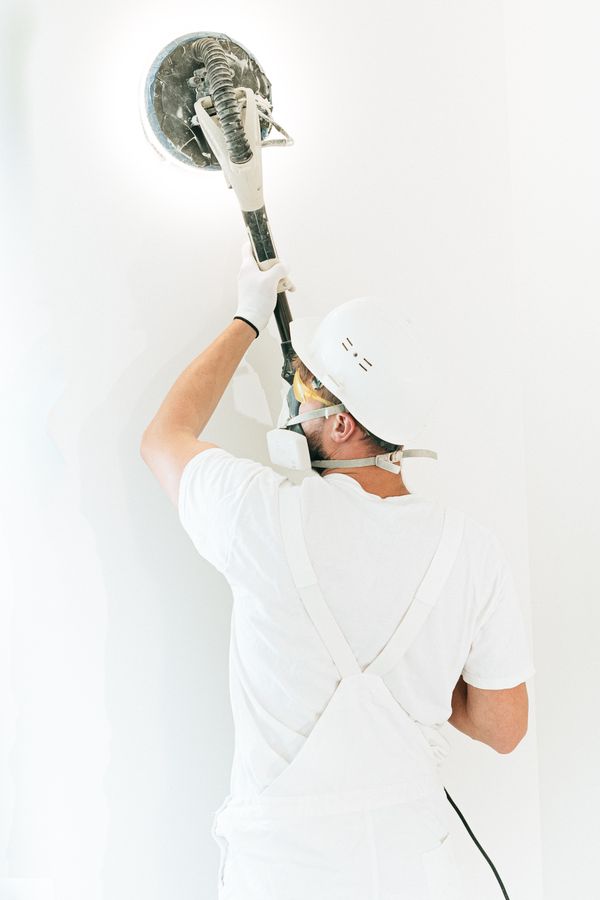 Worker sanding a repaired wall smooth