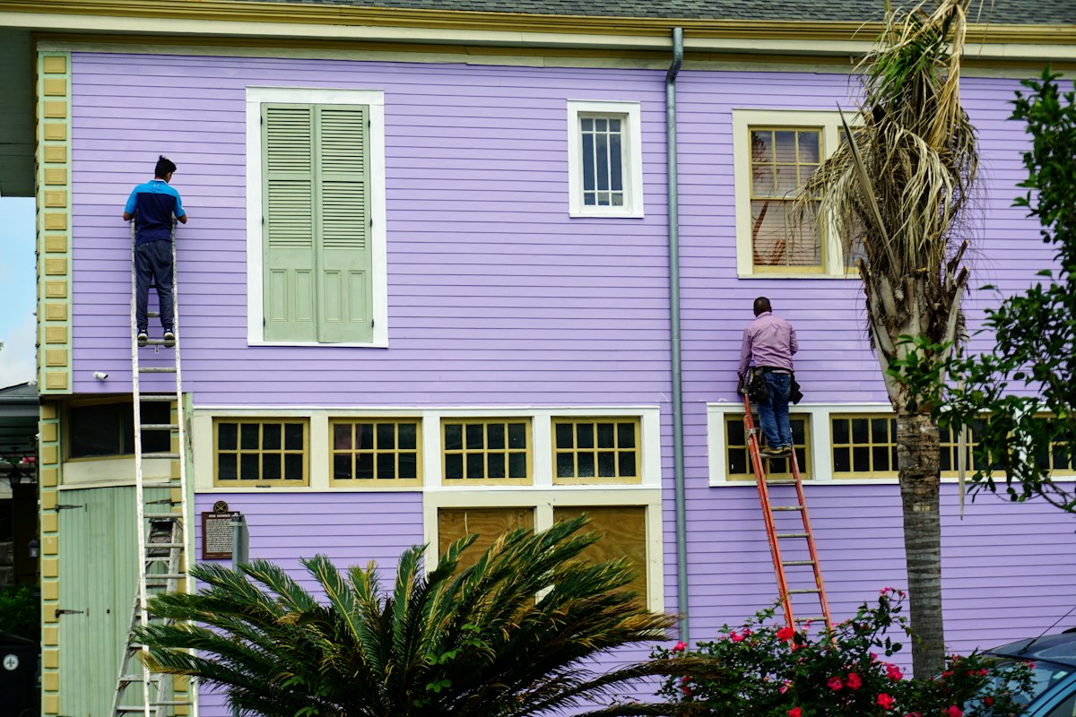 Painters on ladders painting the exterior of a house