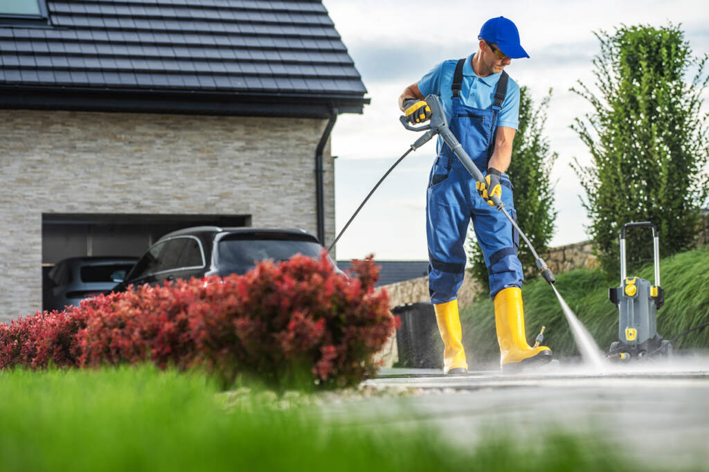 Worker pressure washing a driveway clean